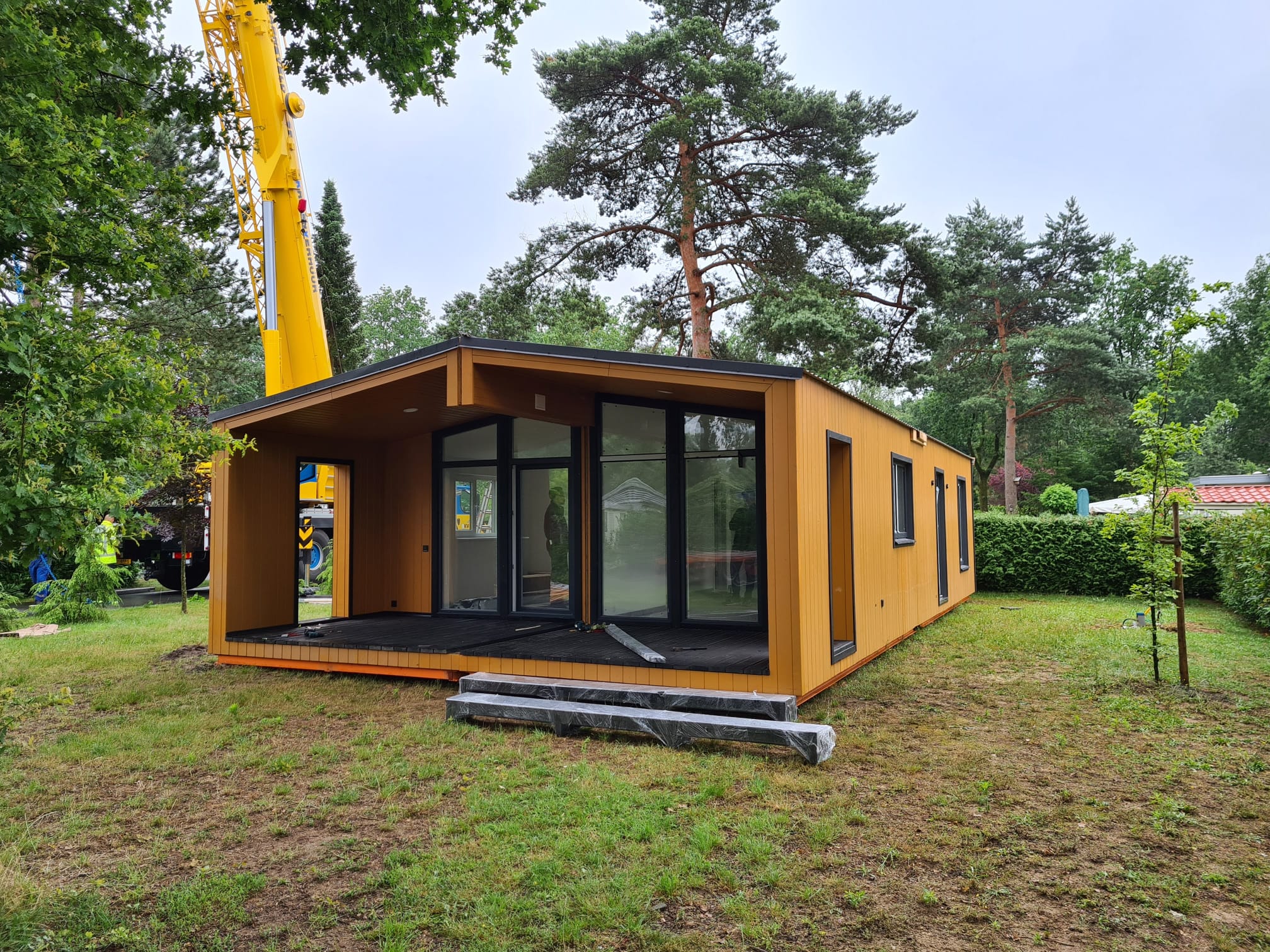 Modulaire woning wordt met een kraan op locatie geplaatst tussen de bomen