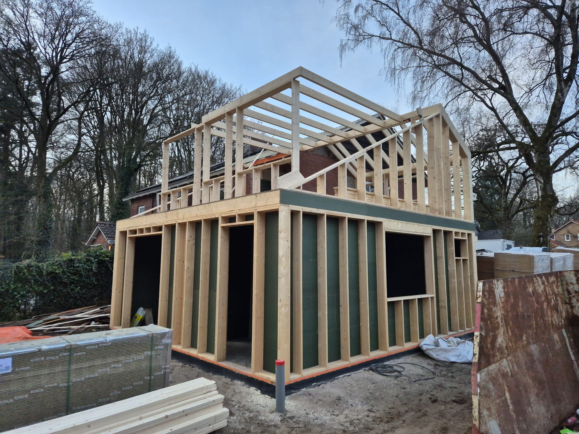 Aanbouw met dakopbouw in houtskeletbouw in aanbouw, het houten frame staat tegen de bestaande bakstenen woning